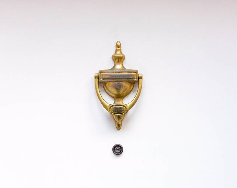 White door with a brass knocker and a peephole