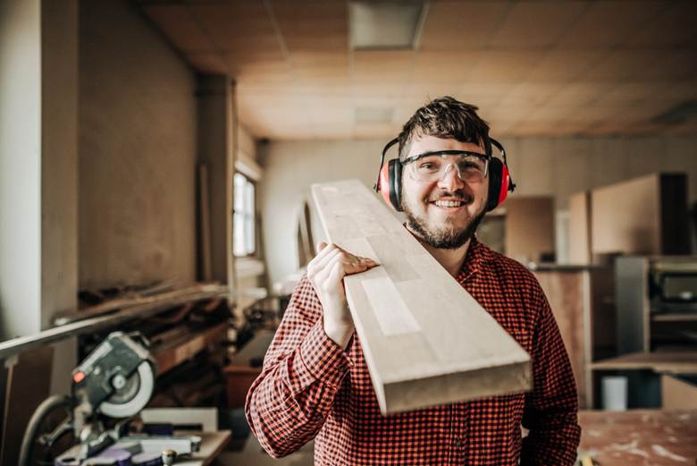 Man carries wooden beam over shoulder